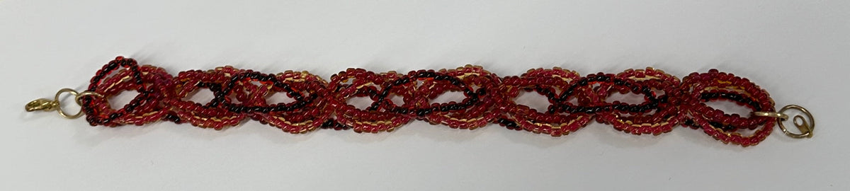A Custom Alltekniq Multi Color Triple Woven Bracelets beaded chain bracelet featuring a braided pattern of red, orange, and dark brown beads, accented with gold-toned metal clasps on a plain white background.